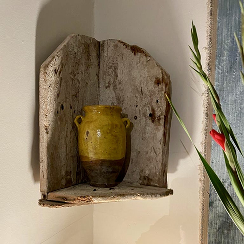 A yellow porcelain far in a wooden corner shelf