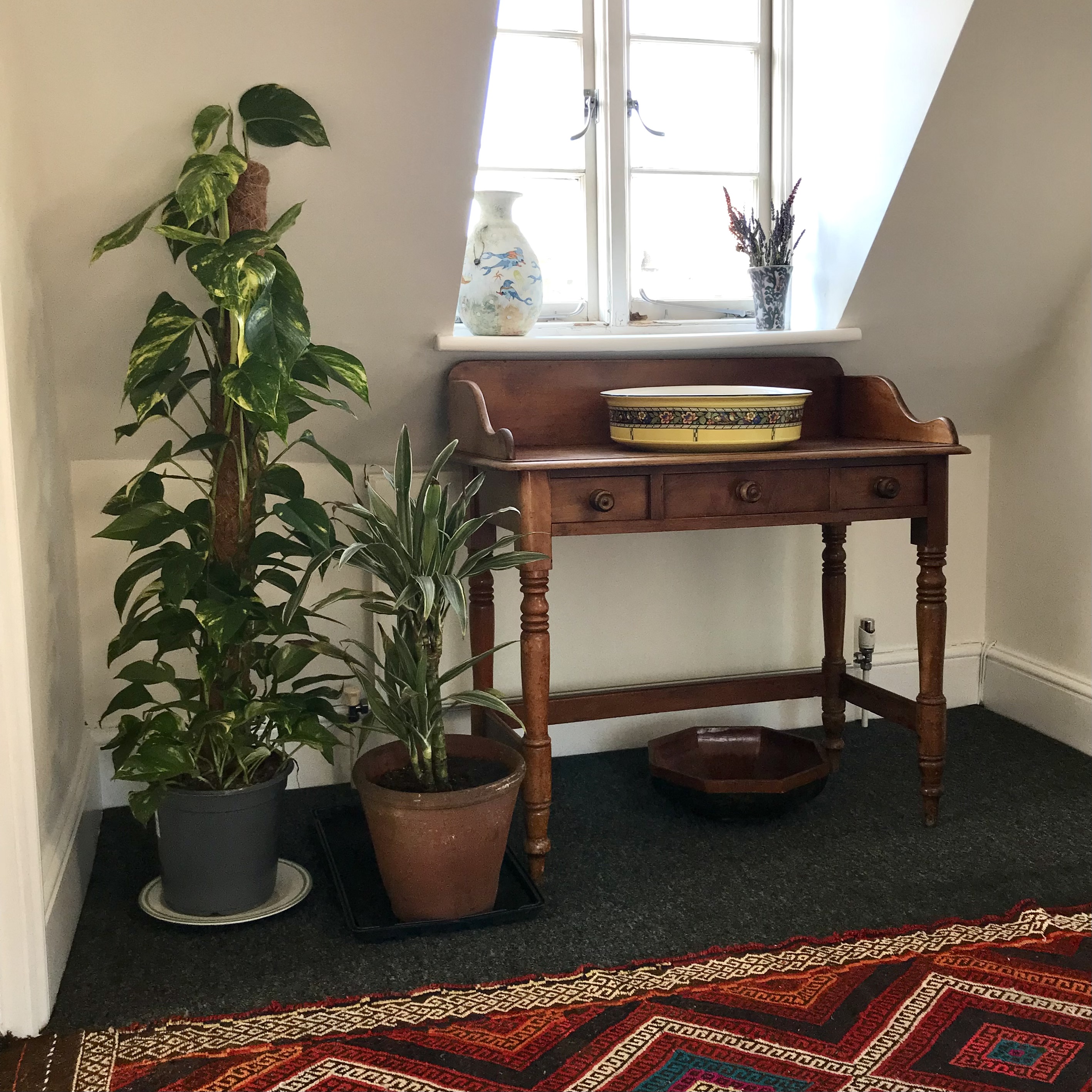 A wooden desk with plants at the top of the stairs