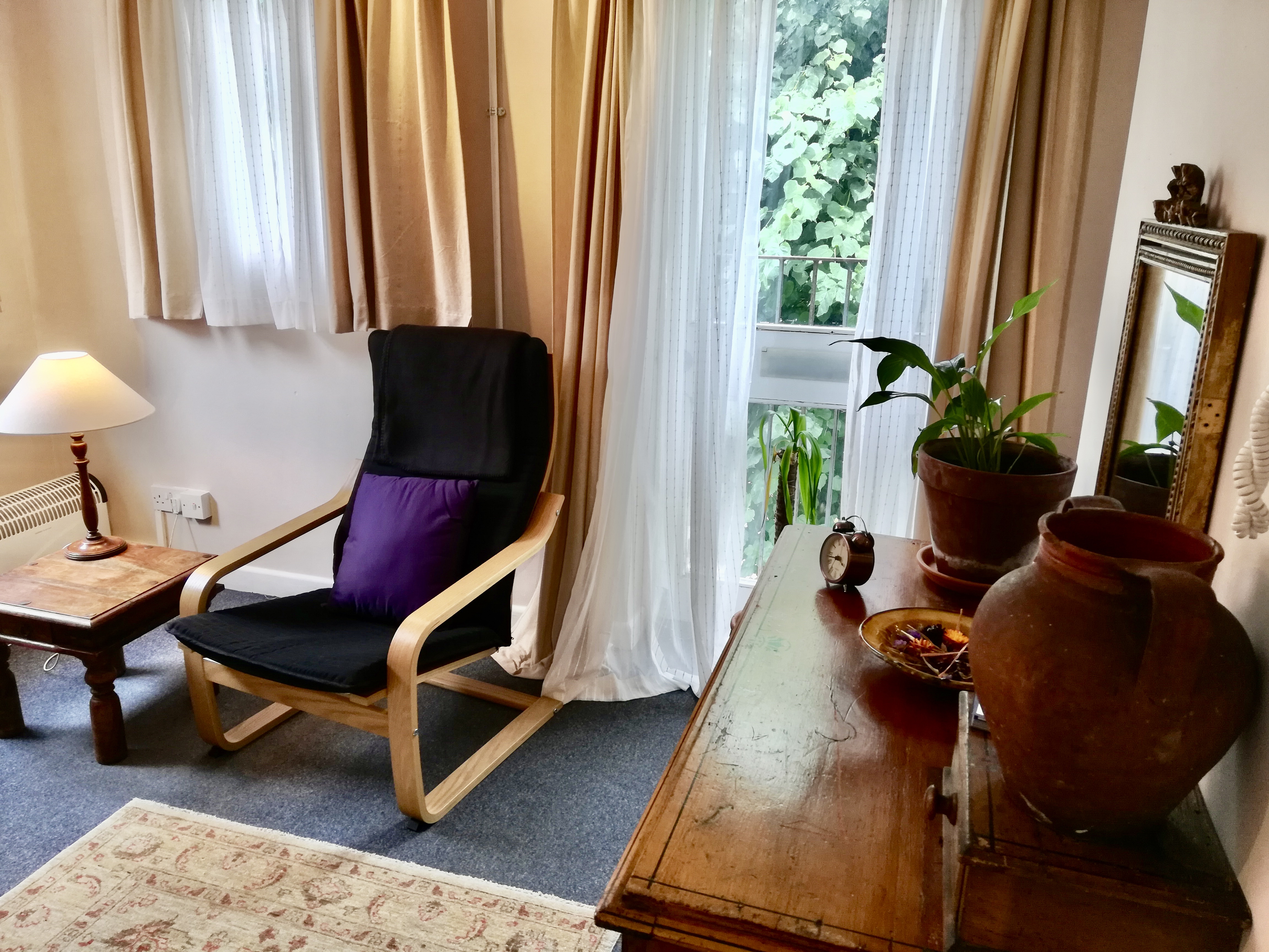 Therapy room with a chair and wooden unit with plant and pots at The Practice Rooms in Oxford