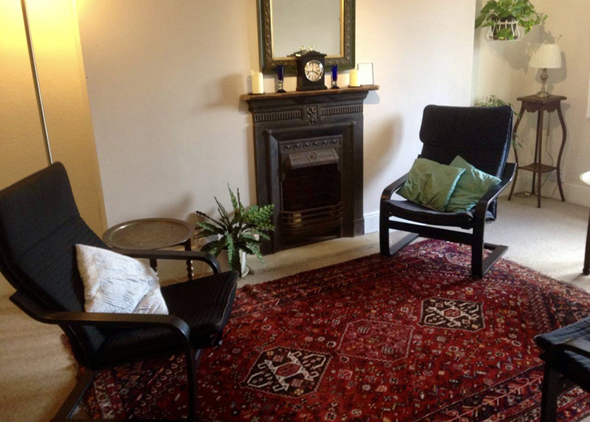 Therapy room with two chairs, fireplace and a red rug at The Practice Rooms in Salisbury