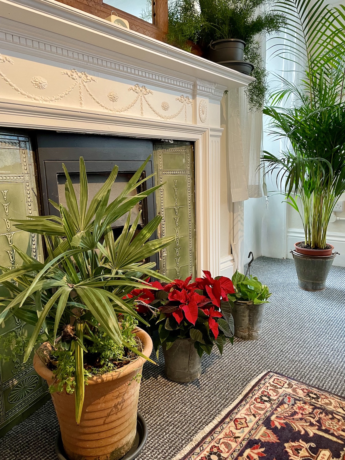 Ornate green fireplace and plants