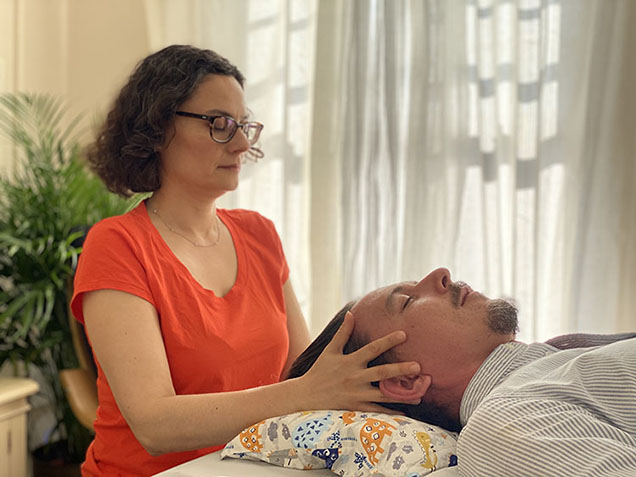 Woman holding the side of a mans face during a craniosacral therapy session
